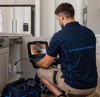 Plumber clearing a blocked toilet in a Bondi bathroom